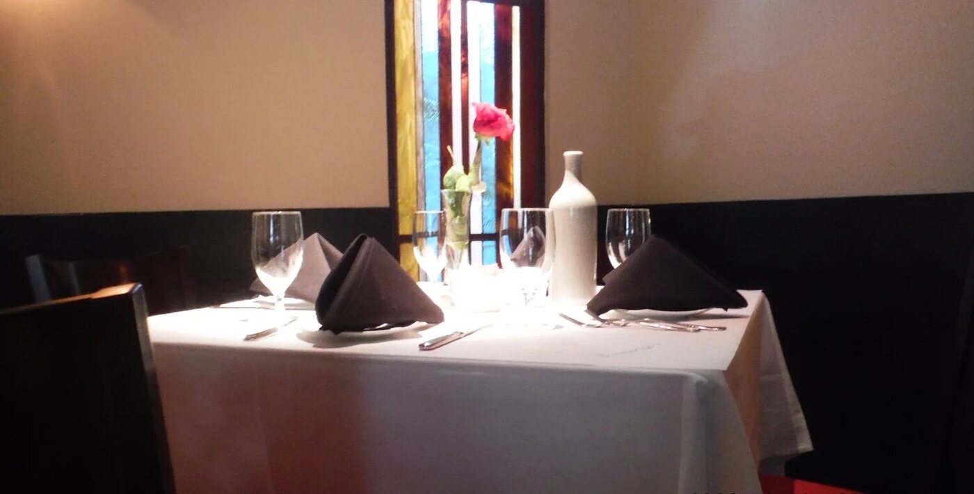 A table set with white linen and wine glasses